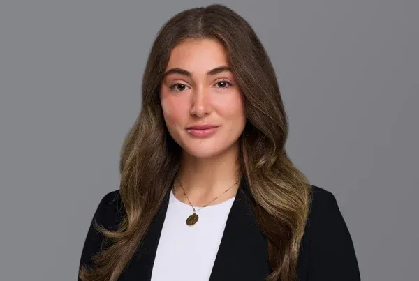 Billi Brandner Professional Portrait Photo Professional headshot of Billi Brandner wearing a black blazer over white top with a necklace against gray background