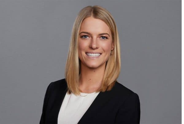 Professional Portrait of Burns V. Professional headshot of a smiling blonde woman in a black blazer and white shirt against a gray background.