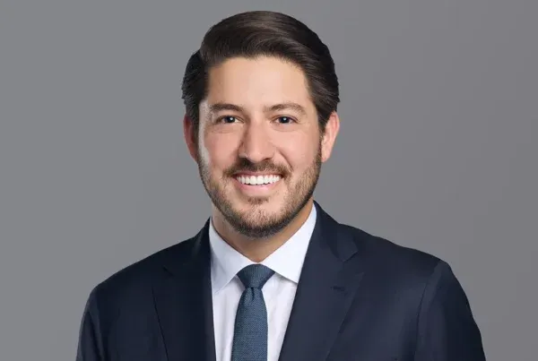 David Diaz Professional Business Portrait Professional headshot of David Diaz wearing a navy suit, white shirt, and dark blue tie against a gray background